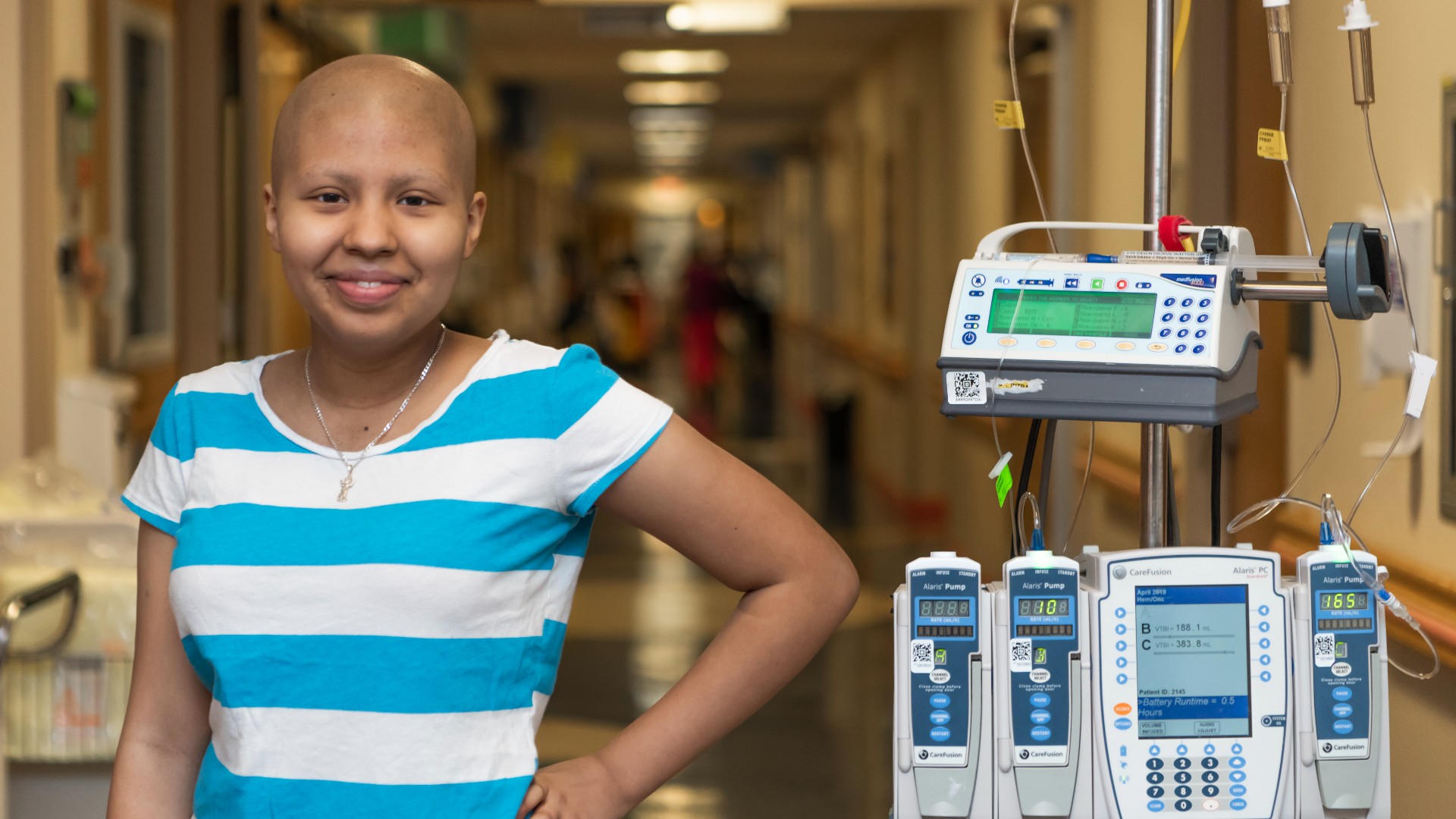 Teenage girl standing in hallway with hand on hip smiling